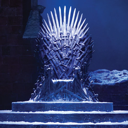 Två ansiktslösa skyltdockor klädda i medeltidsinspirerade kläder står bredvid en tron av svärd i en dunkel, snöig miljö.