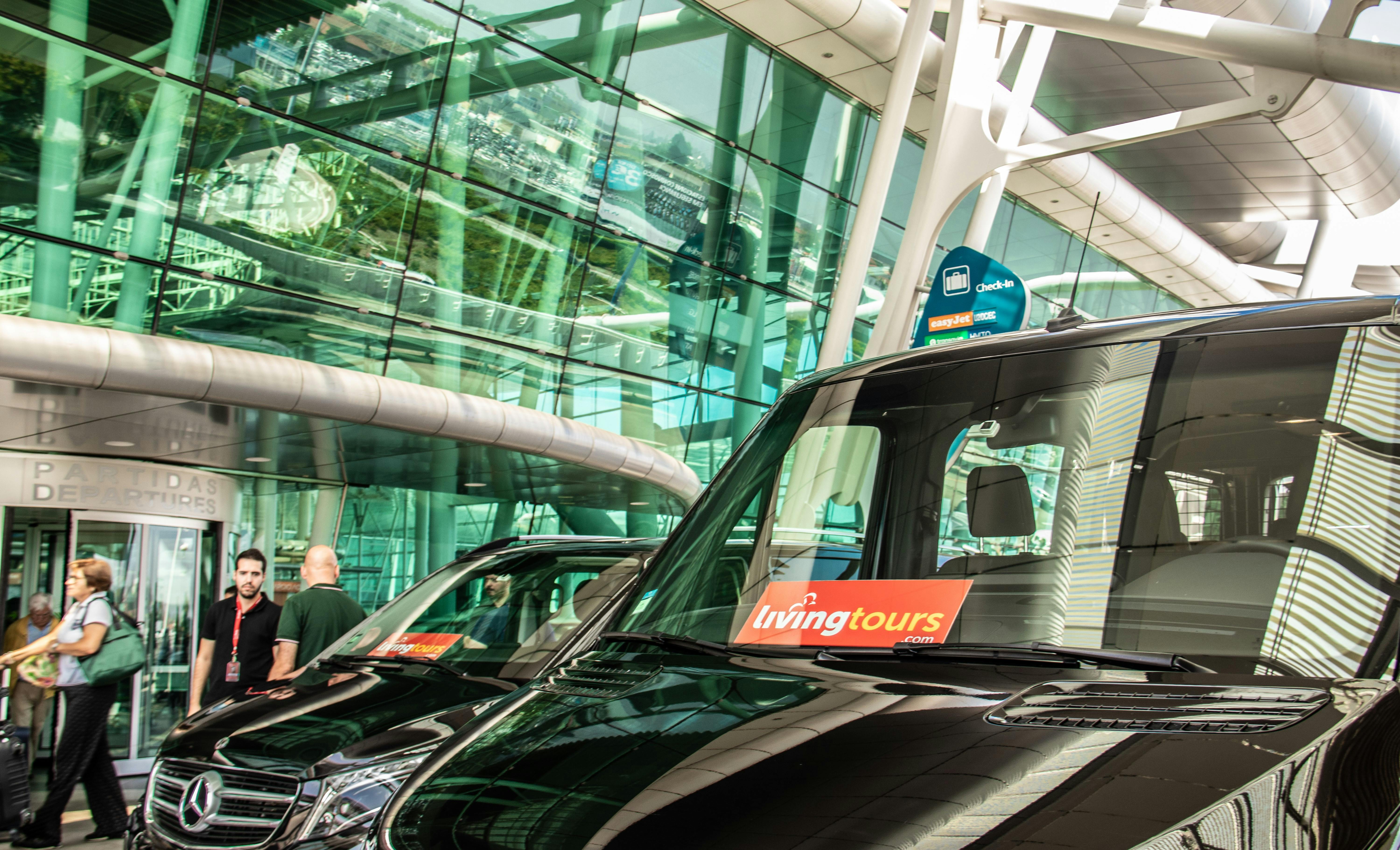People walking by a glass building entrance with reflections, next to parked black vans, one with a "living" logo.