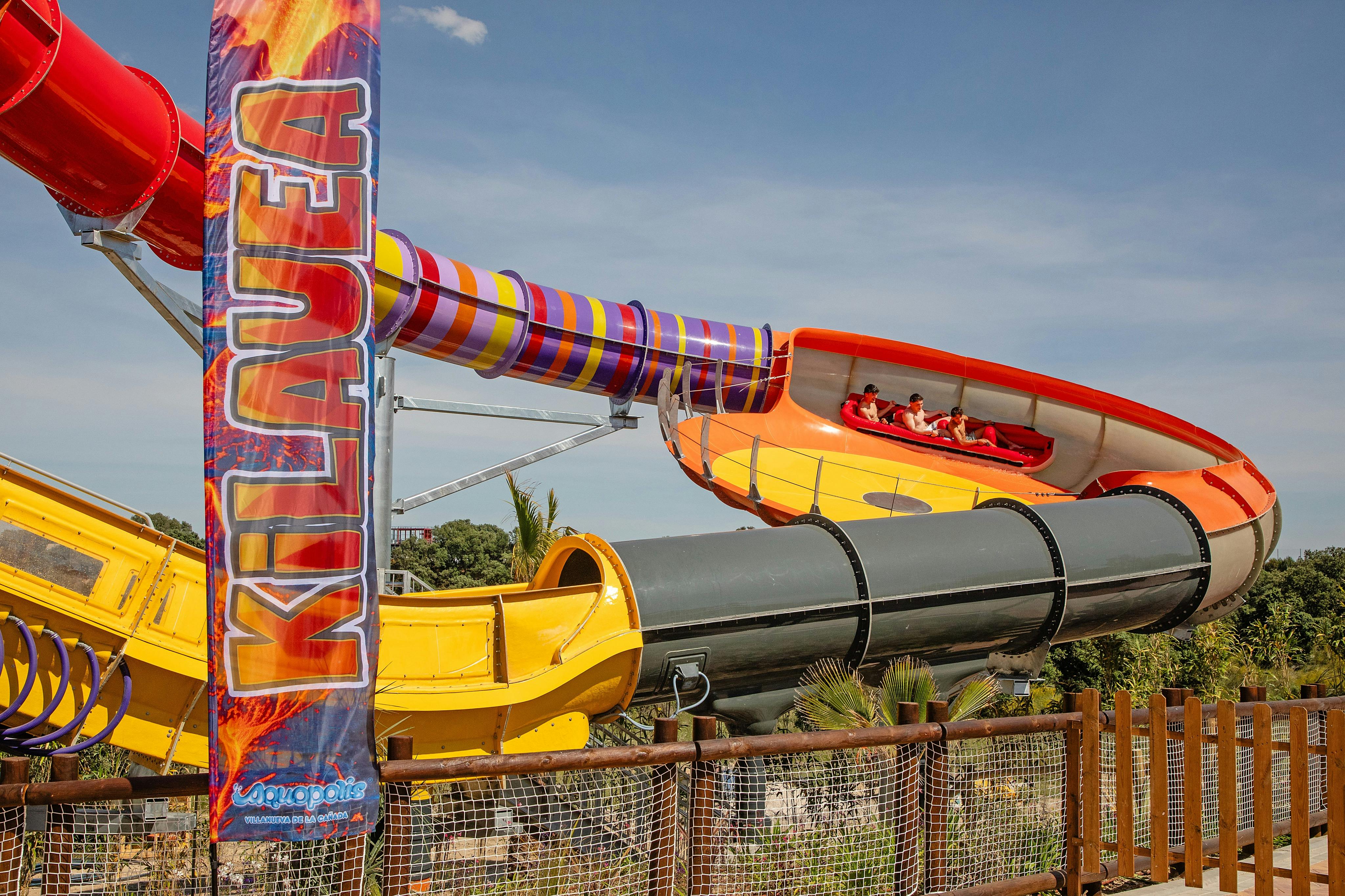 Un toboggan aquatique animé appelé « Kilauea », avec des visiteurs à bord d'un radeau par une journée ensoleillée.