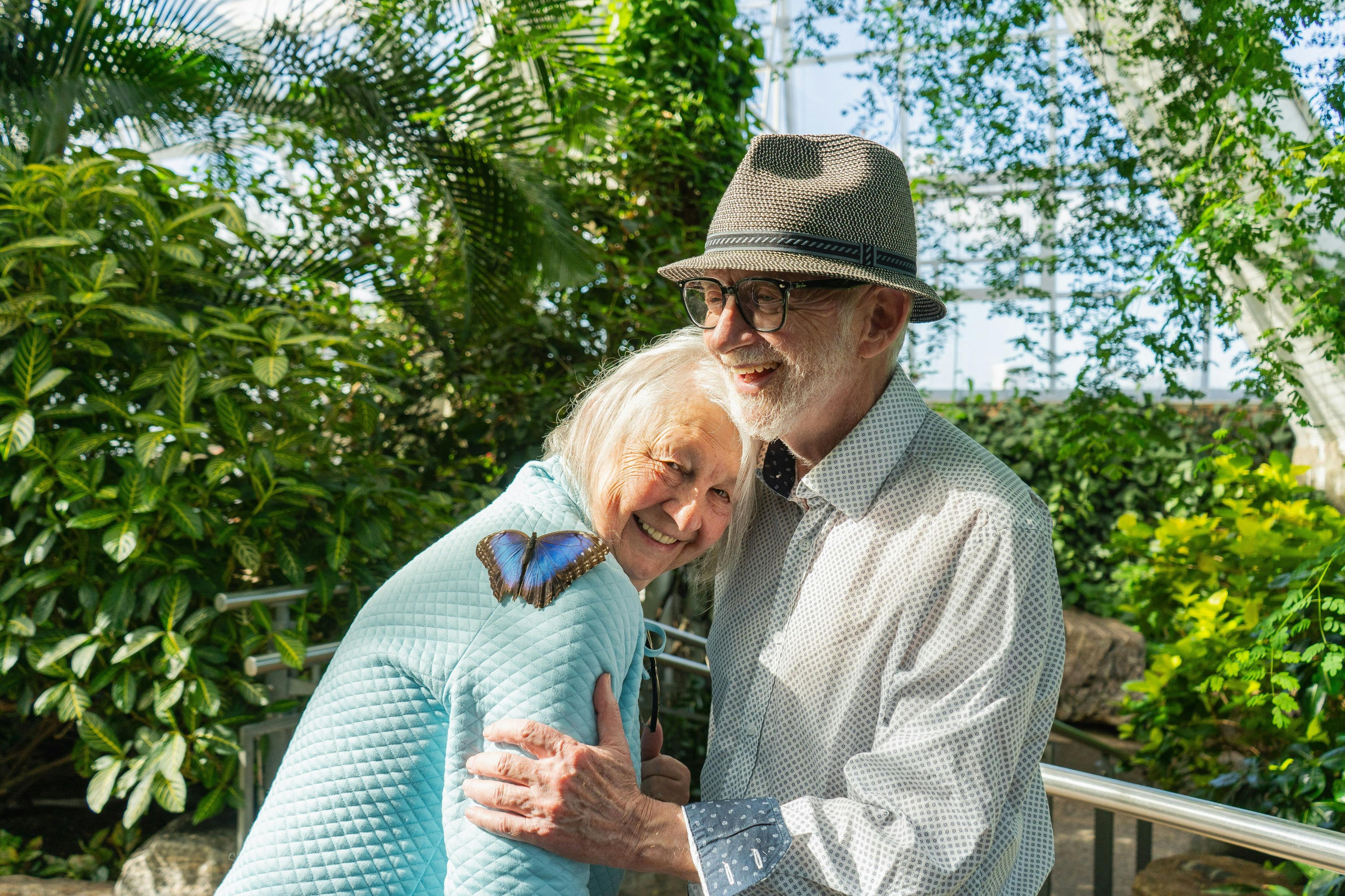 온실에서 따뜻한 미소를 짓고 있는 한 노부부의 어깨에 나비가 걸려 있습니다.
