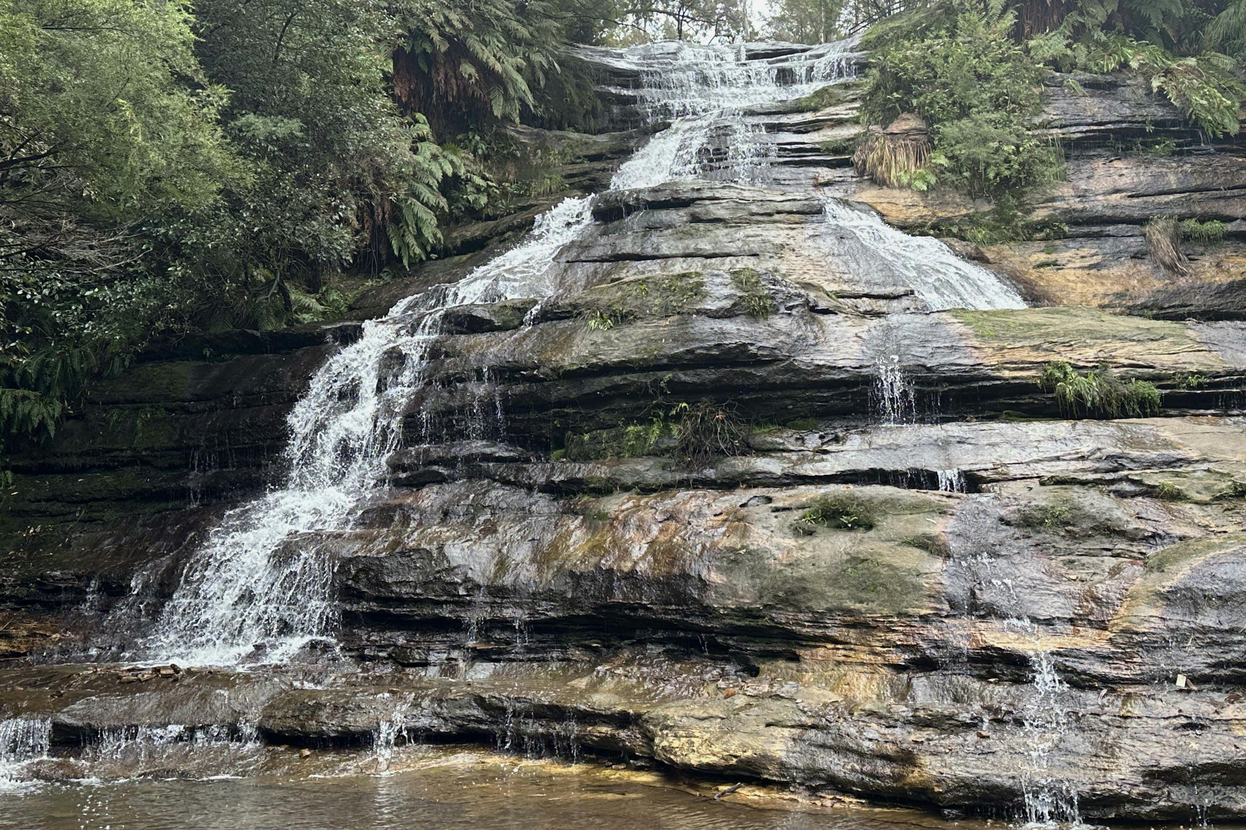 Spaziergang auf Trittsteinen am Fuße der beeindruckenden Katoomba Cascades Waterfalls