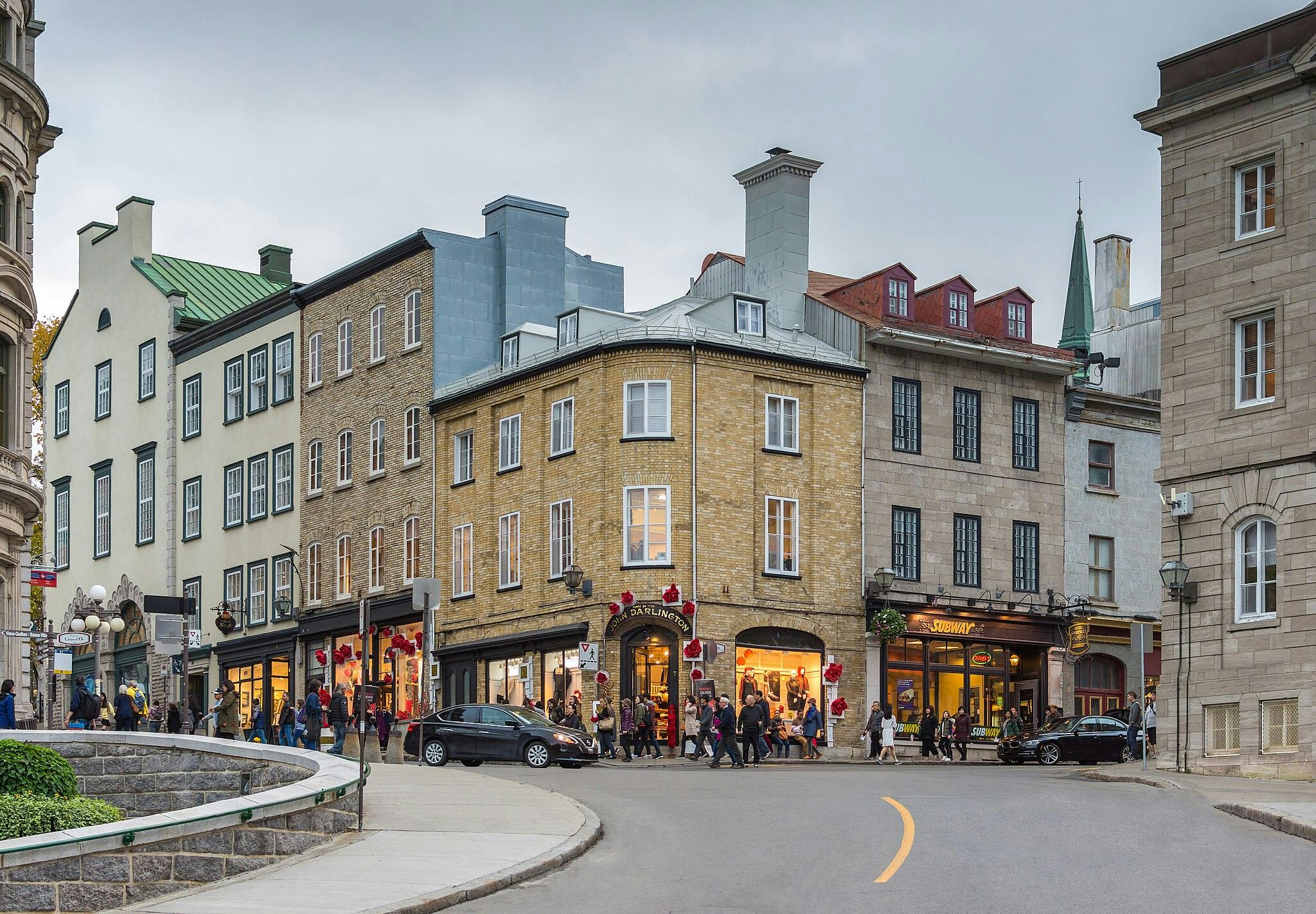 La gent passa per les botigues d'un carrer ple d'edificis històrics en un dia nublat.