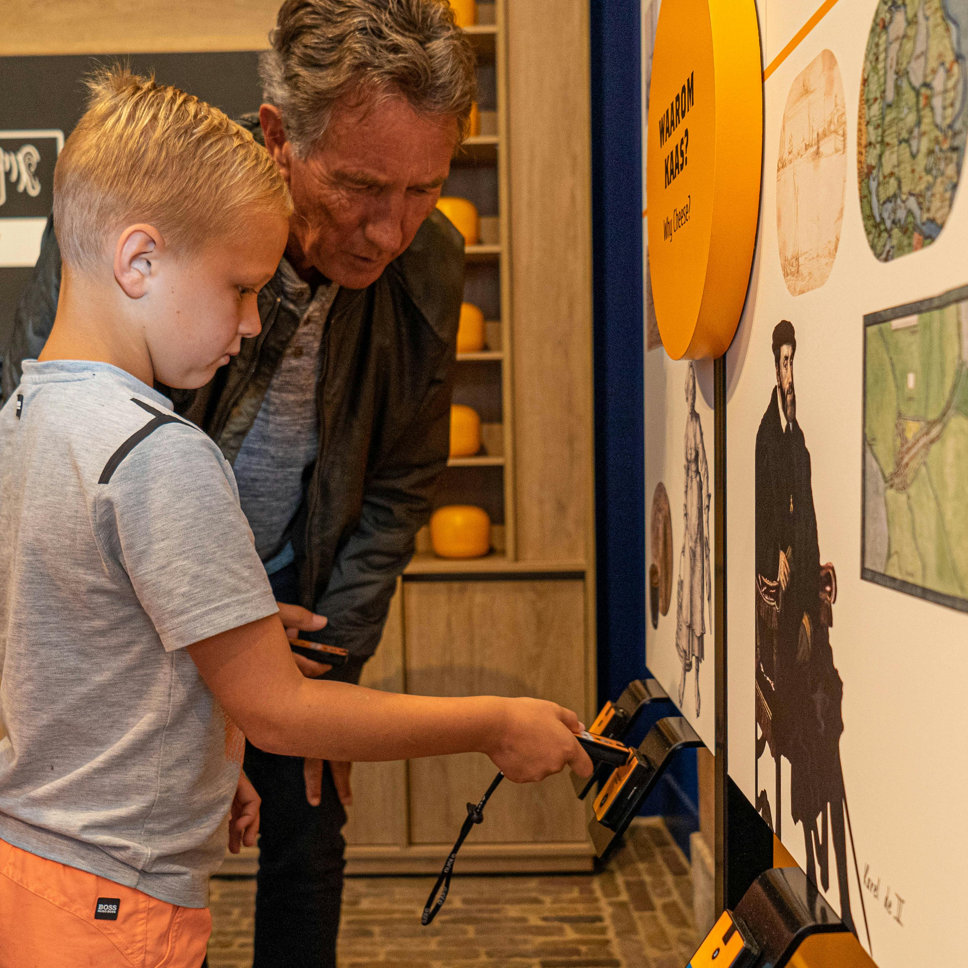 A child and an adult examine a wall display with historical illustrations and maps inside a museum exhibit.