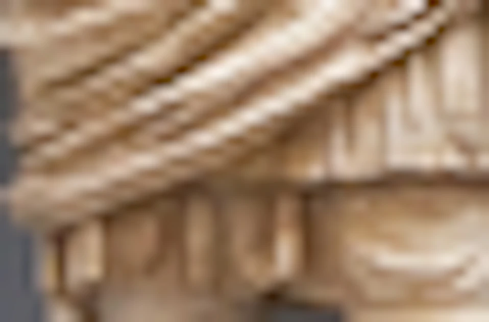 A person standing in front of three marble statues displayed in arched alcoves within a museum setting.