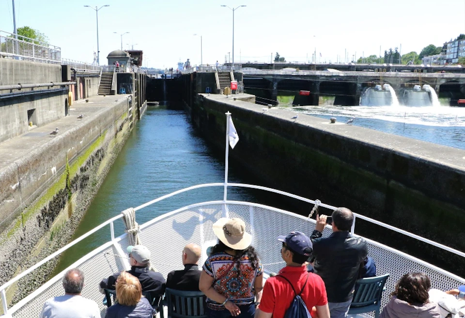 People on the bow of an Argosy boat as it approaches the Locks. Concrete walls are on either side