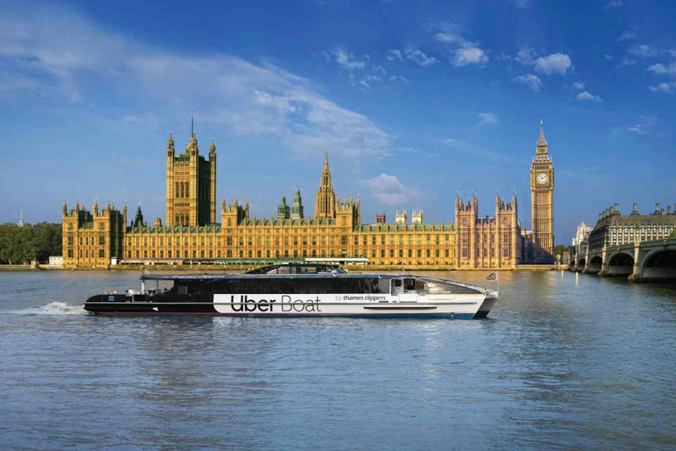 A boat labeled 'Uber Boat by Thames Clippers' on a river with the Houses of Parliament and Big Ben in the background.