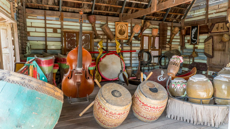 A collection of traditional musical instruments, including drums and a double bass, displayed inside a rustic wooden structure.