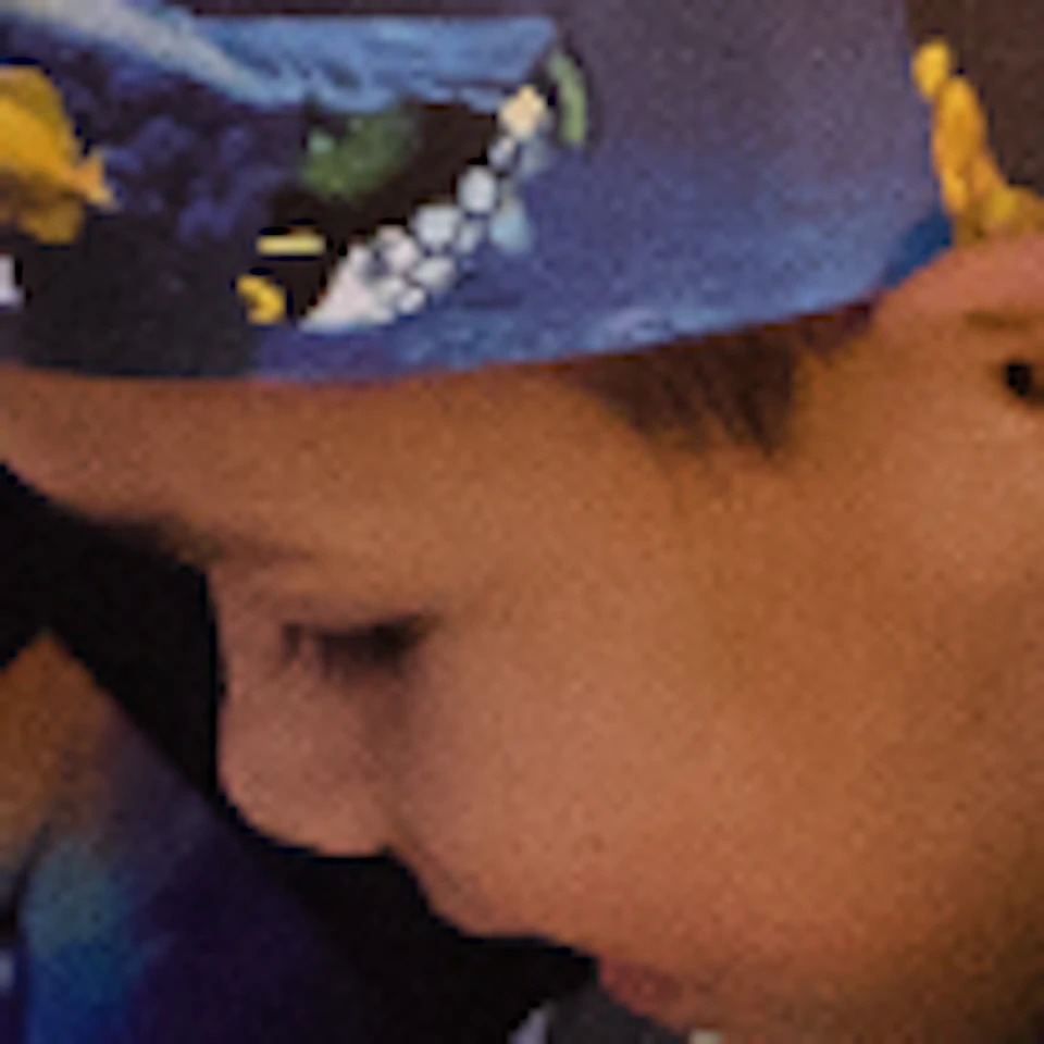 A child touches a starfish in a touch pool, supervised by two adults in an aquarium setting.