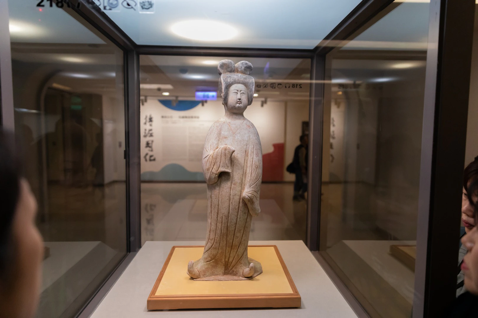 A statue of a woman in traditional attire displayed in a glass case inside a museum.