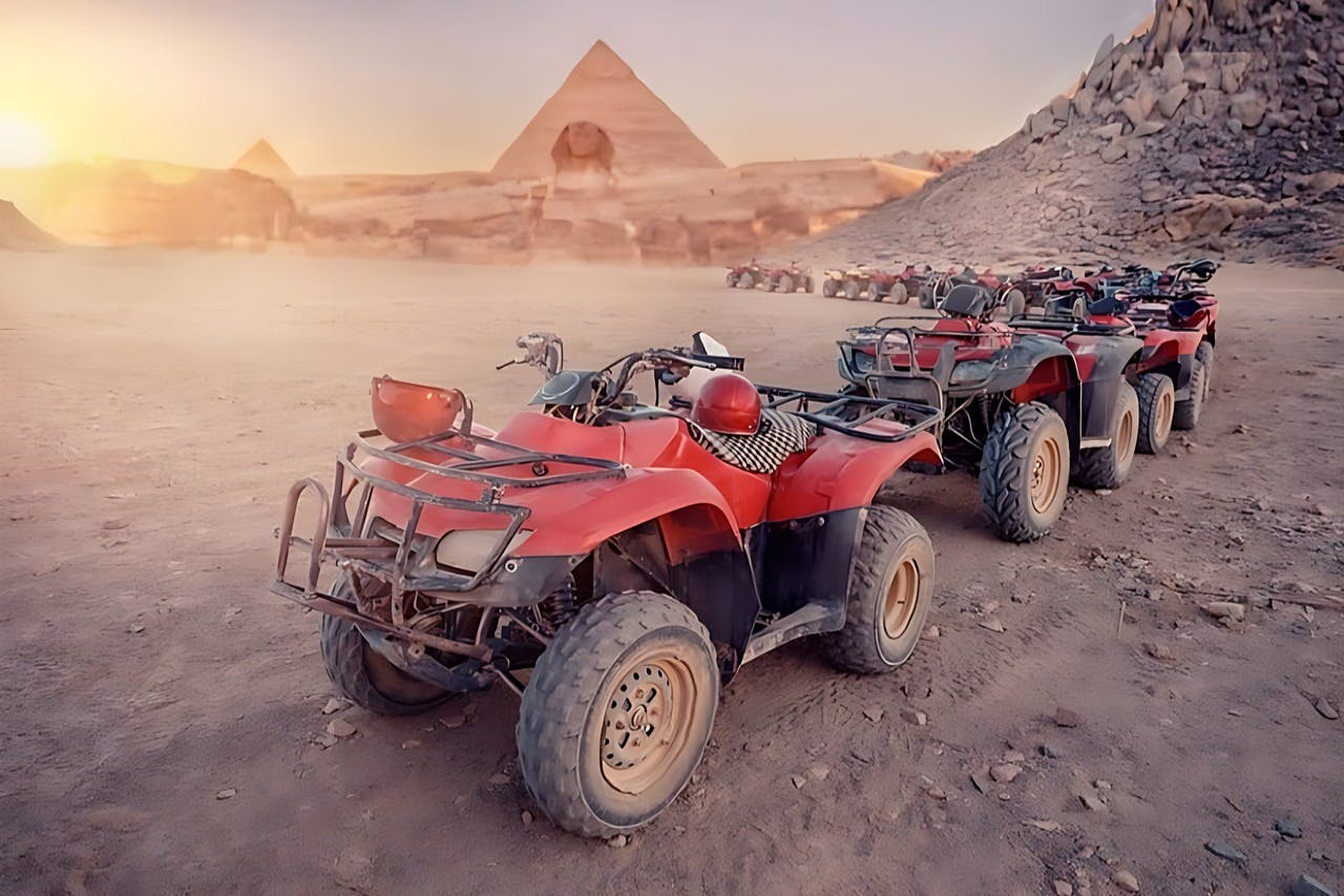 几辆红色全地形车停在沙漠景观上，背景是金字塔和岩石周围。
