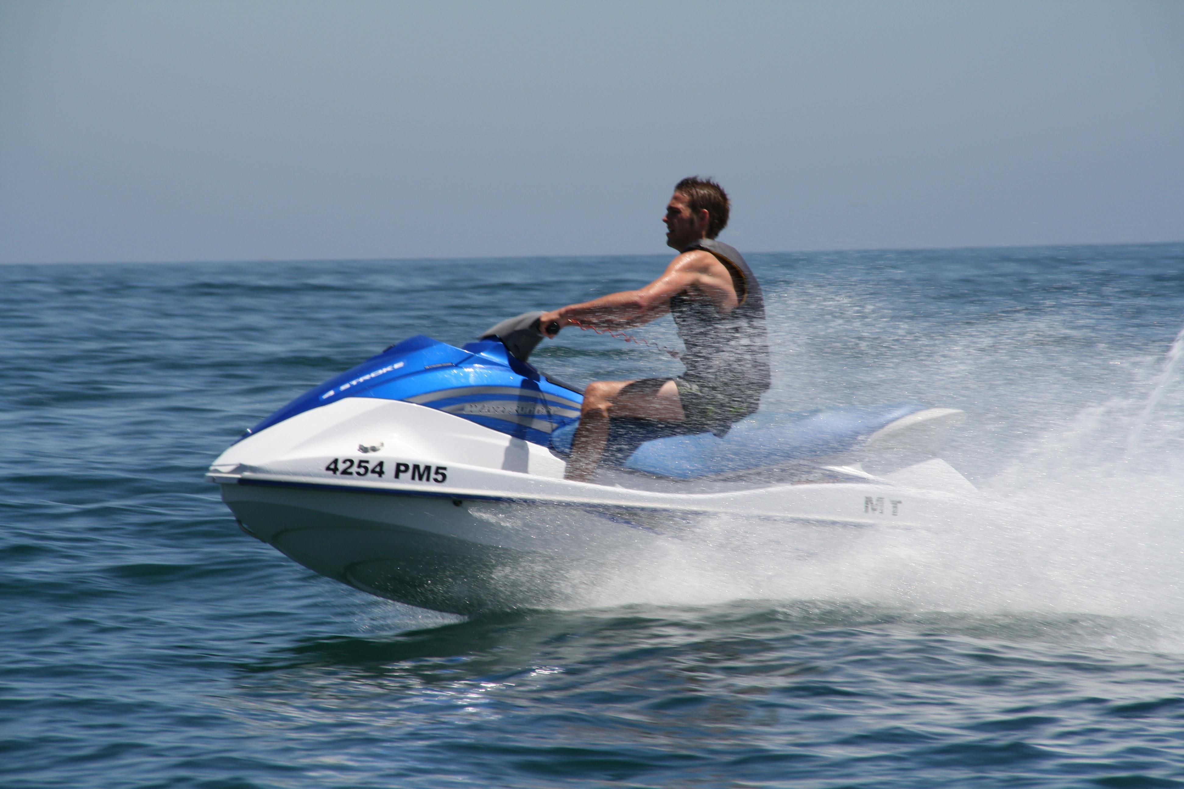 穏やかな海の上で青と白のジェットスキーに乗って、大きな水のスプレーを作り出している人。