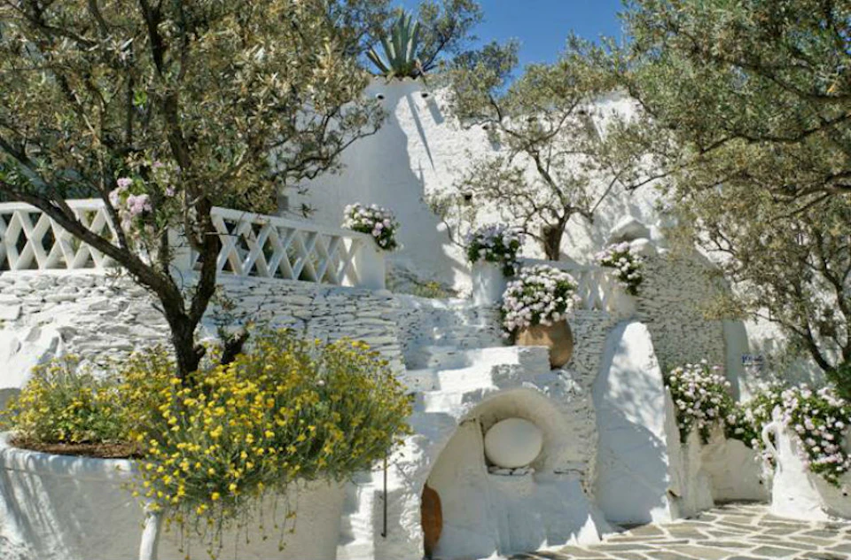 White stone steps and walls adorned with yellow flowers and greenery, under a clear blue sky.