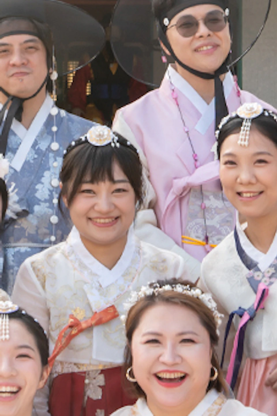 A group of people wearing traditional Korean hanbok poses in front of a traditional building with colorful decorations.