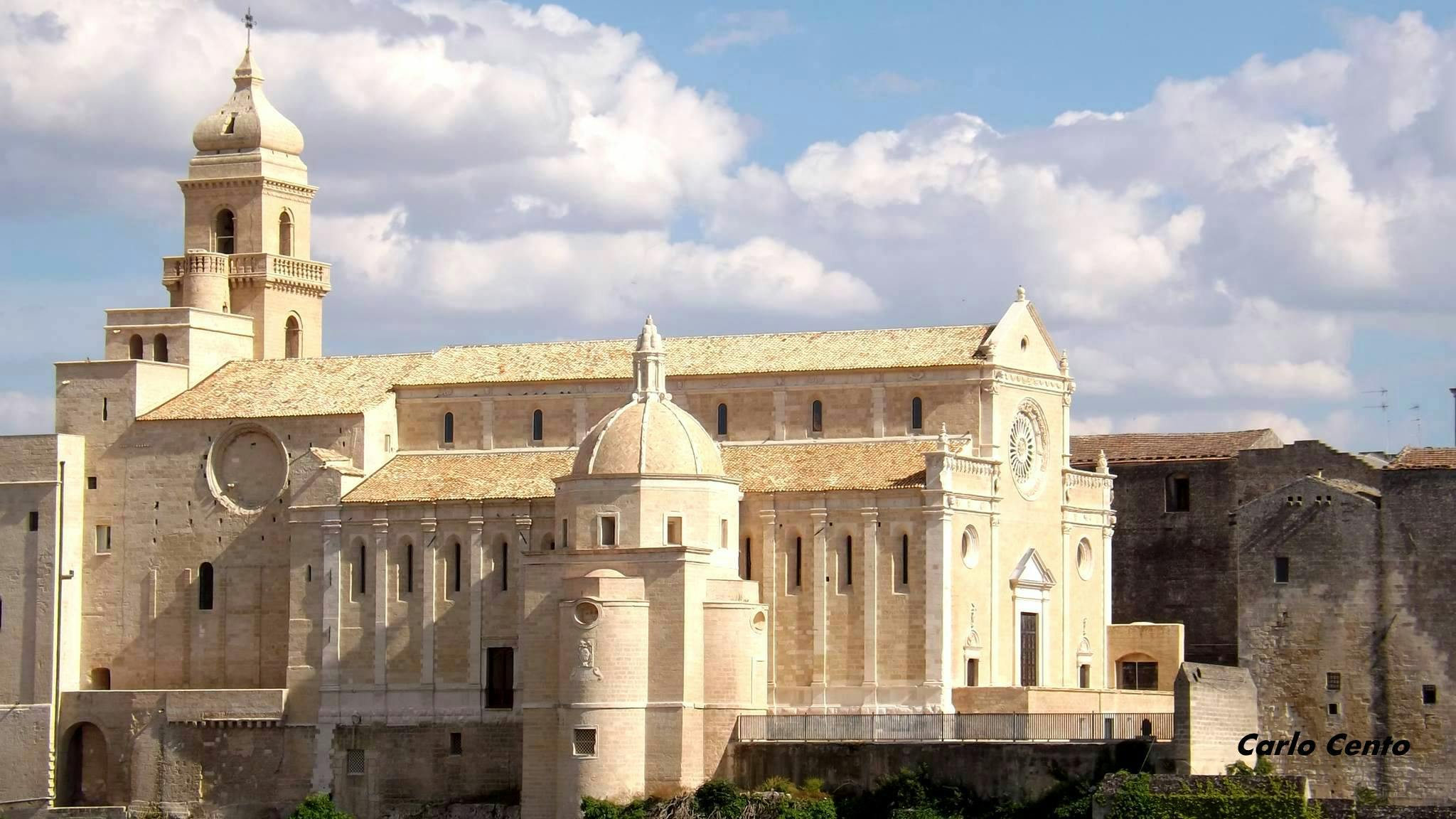 Large historic building with multiple arches, a dome, and ornate architectural details under a partly cloudy sky.