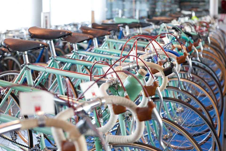 Rows of vintage bicycles with leather seats and colorful handlebars lined up in a showroom.