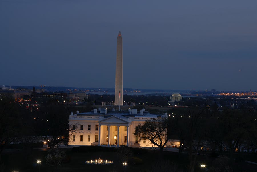 黄昏时分，白宫灯火通明，背景可见华盛顿纪念碑和杰斐逊纪念碑。