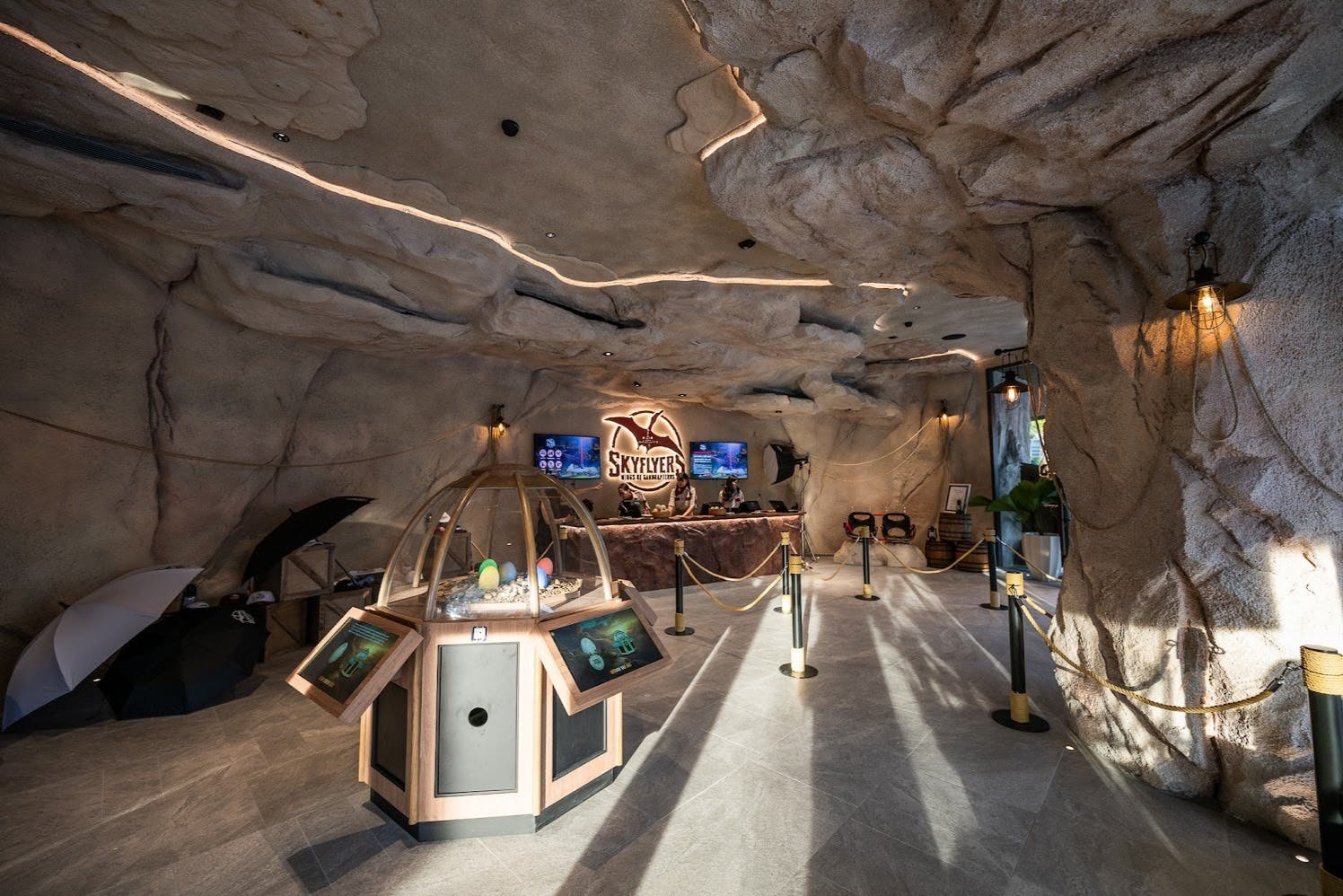 An indoor space with a cave-like design, featuring a display case, a counter with a 'Skyflyer' sign, and decorative lighting.