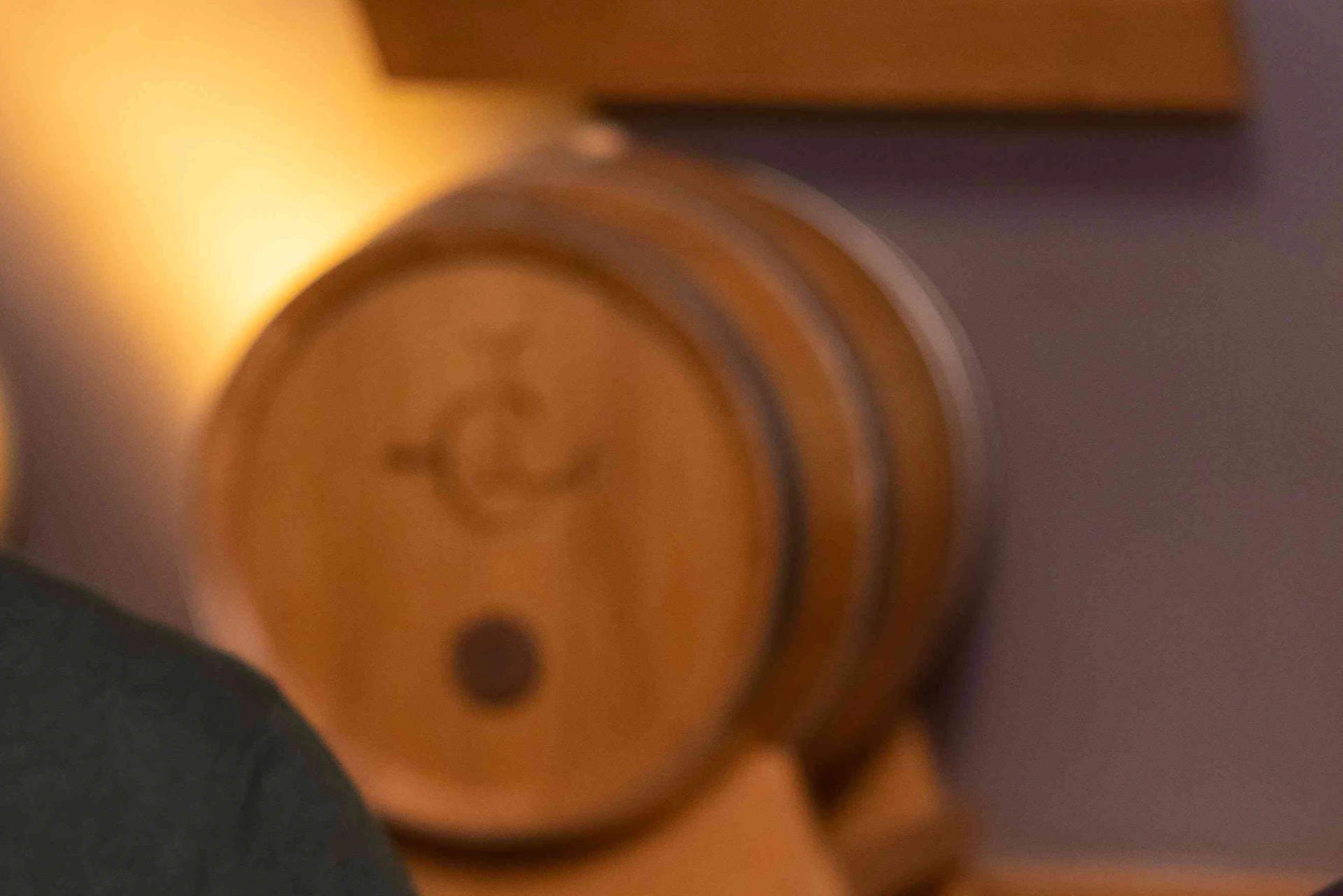 Two men at a table passing a plate of assorted charcuterie with wine glasses and barrels in the background.