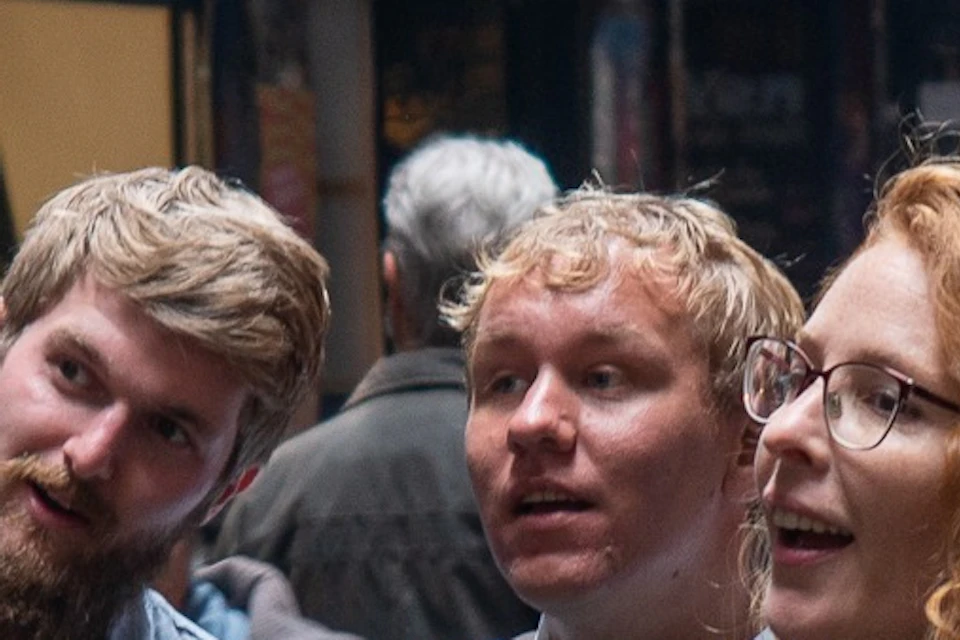 A group of people in a narrow urban alleyway, one person gesturing as if explaining something.