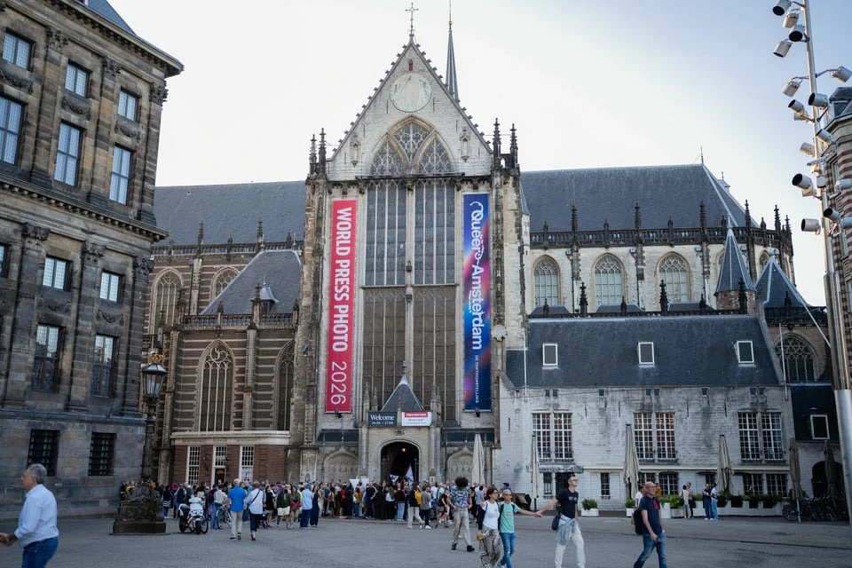 A historic church with banners for a 2026 World Press Photo event and a crowd of people gathered in front.