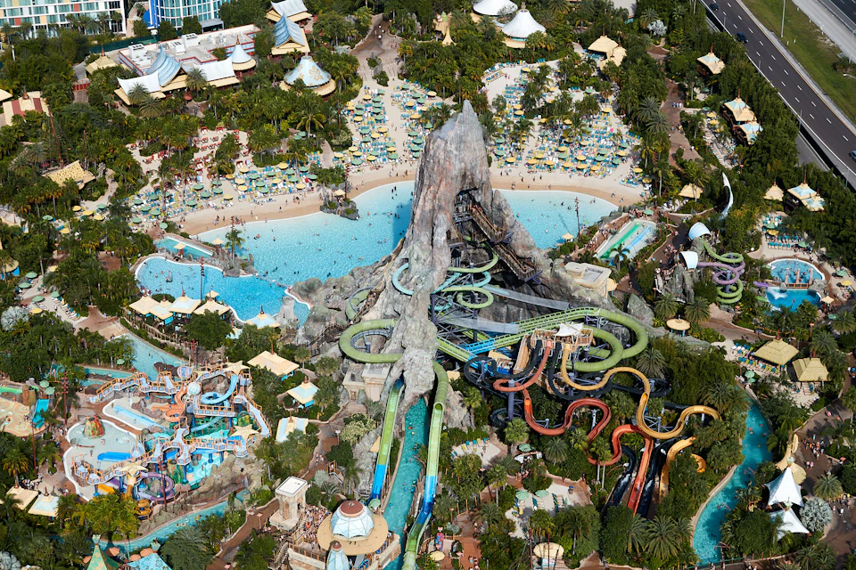 Aerial view of a water park featuring a volcano-themed structure with water slides and pools surrounded by greenery.