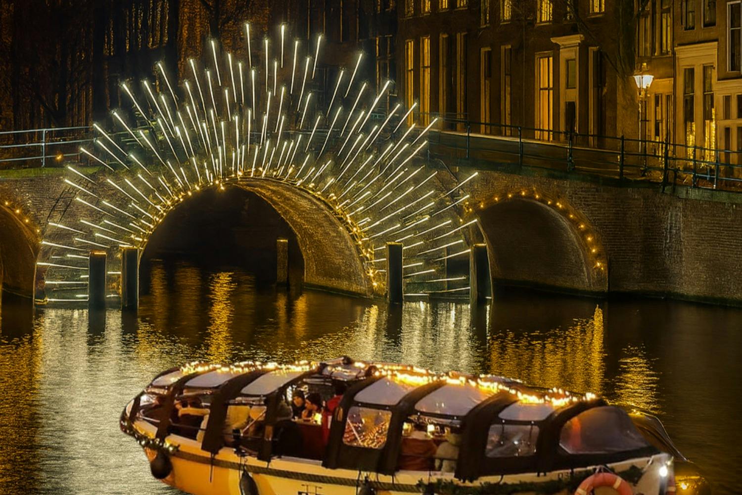 En båd prydet med lys flyder på en kanal under en oplyst buegang i en by om natten.