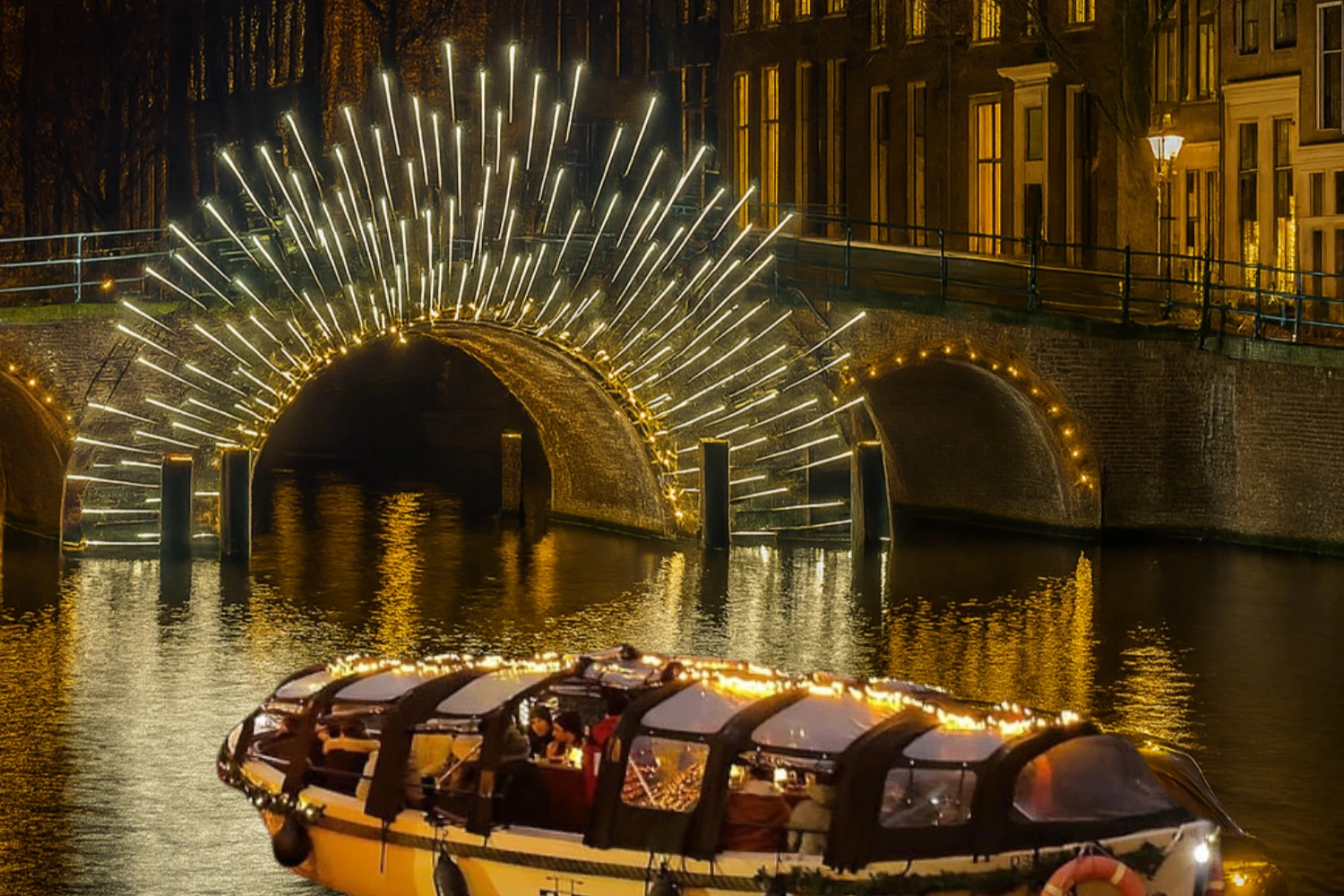 A boat adorned with lights floats on a canal beneath an illuminated archway in a city at night.