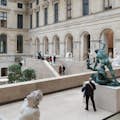 Ein Mann steht neben einer Statue im Inneren des Richelieu-Flügels des Louvre-Museums