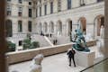 Homem de pé ao lado de uma estátua na ala Richelieu do Museu do Louvre
