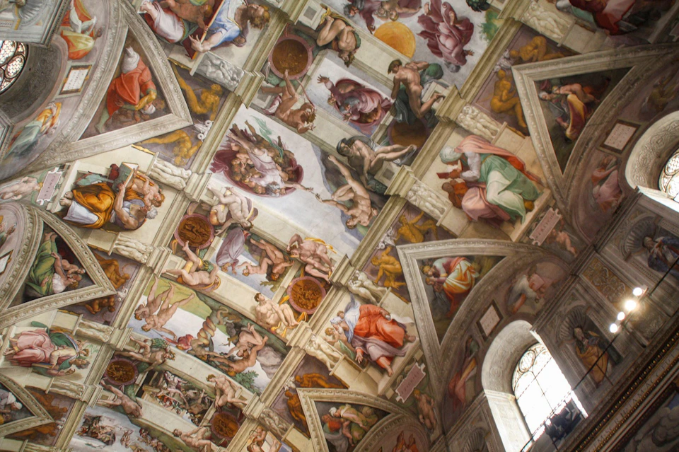 A detailed fresco on a vaulted ceiling, featuring numerous figures, vibrant colors, and intricate architectural elements.