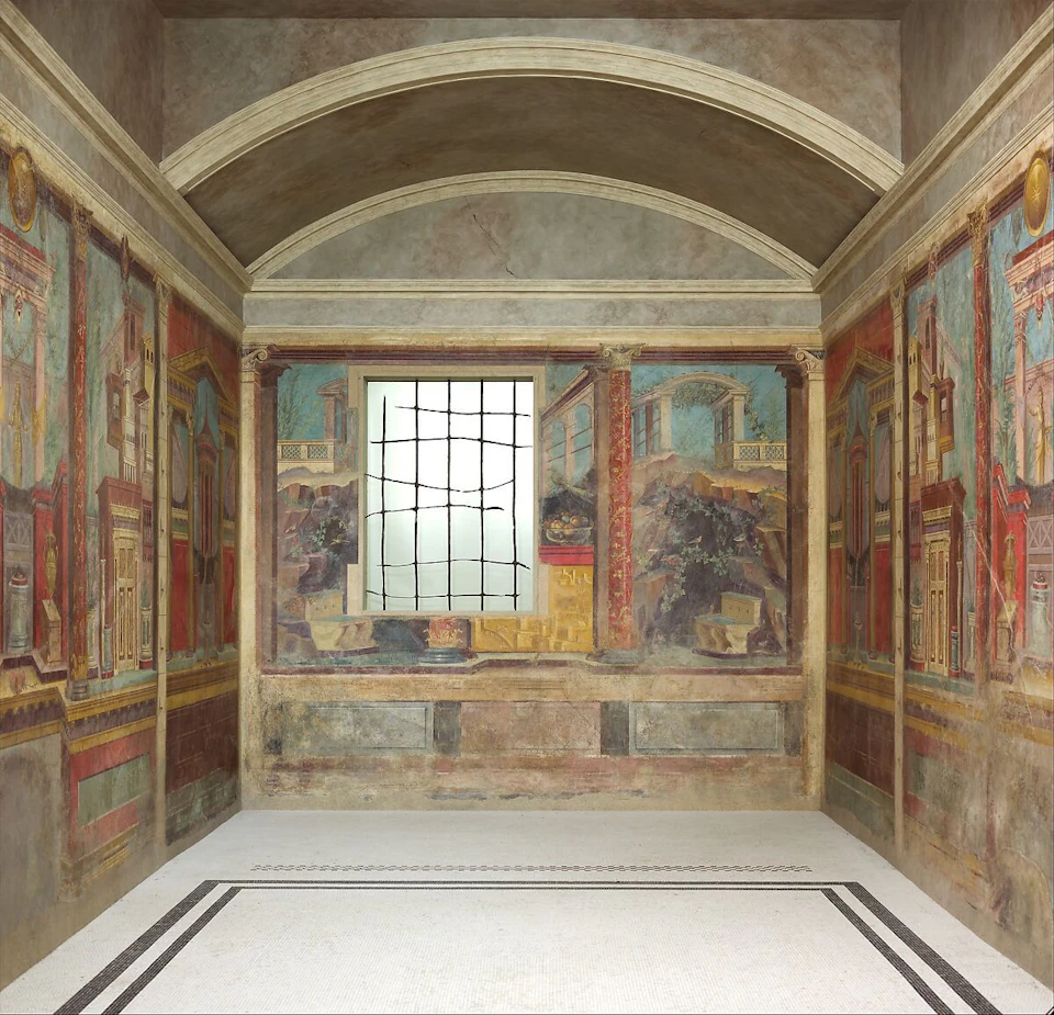 An empty room with detailed frescoes depicting architectural scenes and a window with a grid pattern in the center wall.