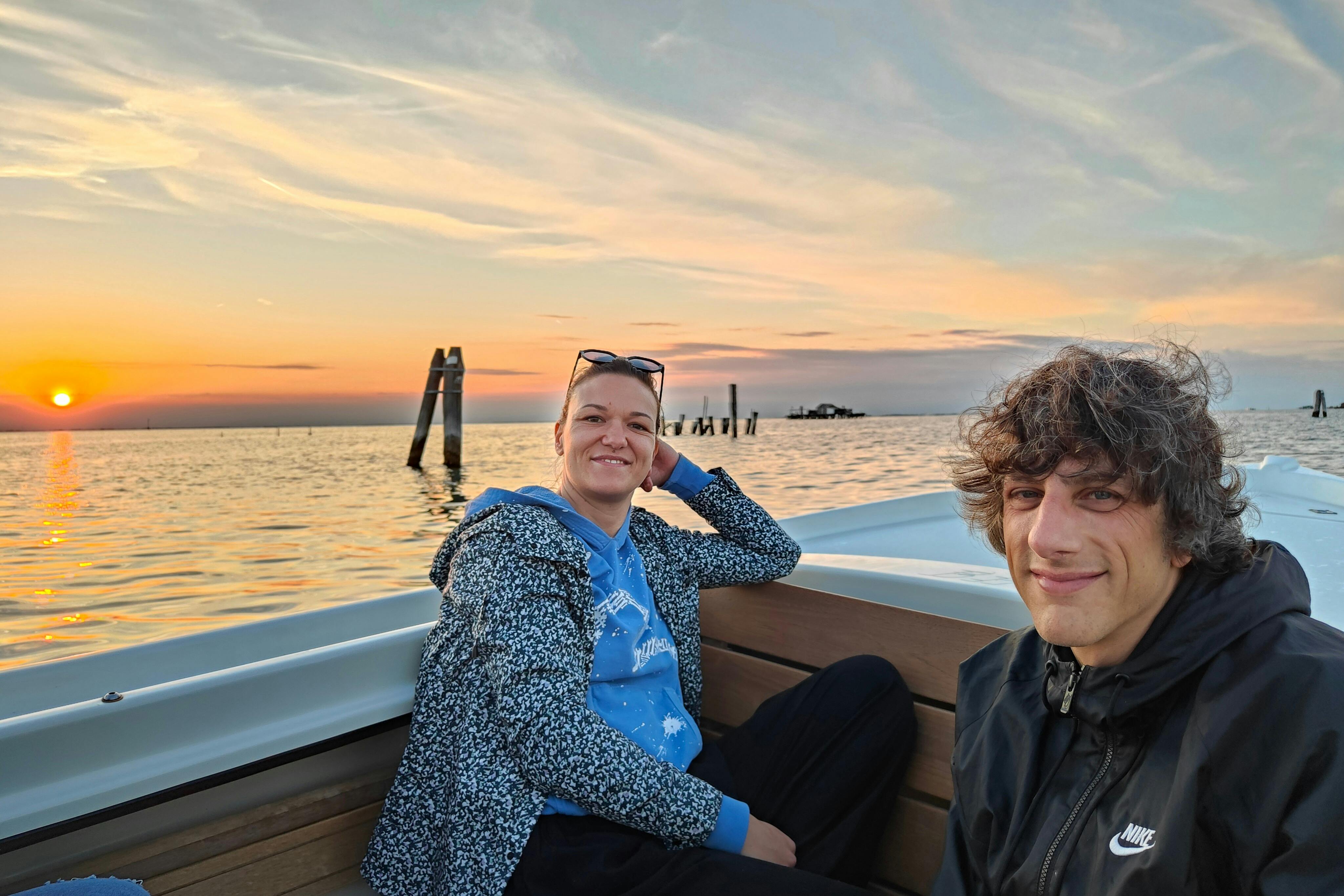 Kunder under båttur med vacker solnedgång i bakgrunden