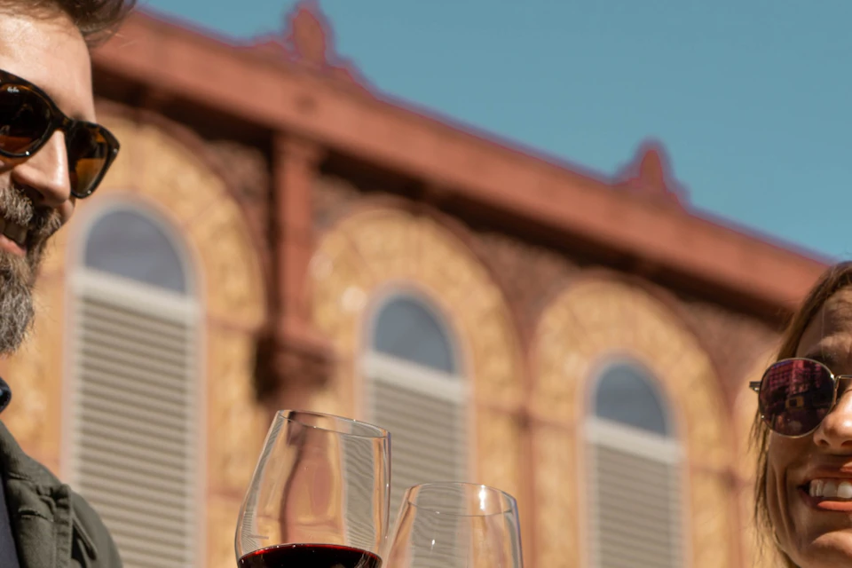 A man and a woman holding a glass of wine while doing a wine tour in Barcelona.