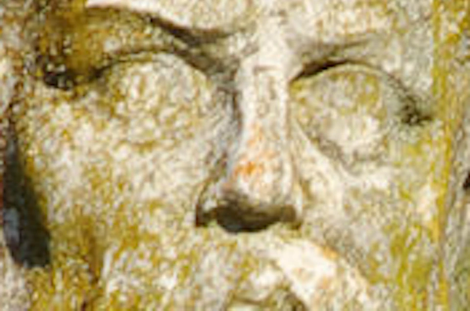 Ancient stone statue depicting a bearded man and a child, with vines climbing the building in the background.