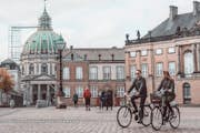 Duas pessoas em bicicletas na Praça Amalienborg