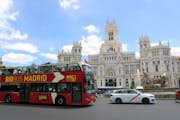 En stor buss kör förbi Cybele Palace i Madrid