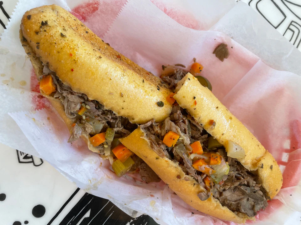A sandwich filled with shredded meat, diced carrots, and vegetables, served on a paper-lined tray.