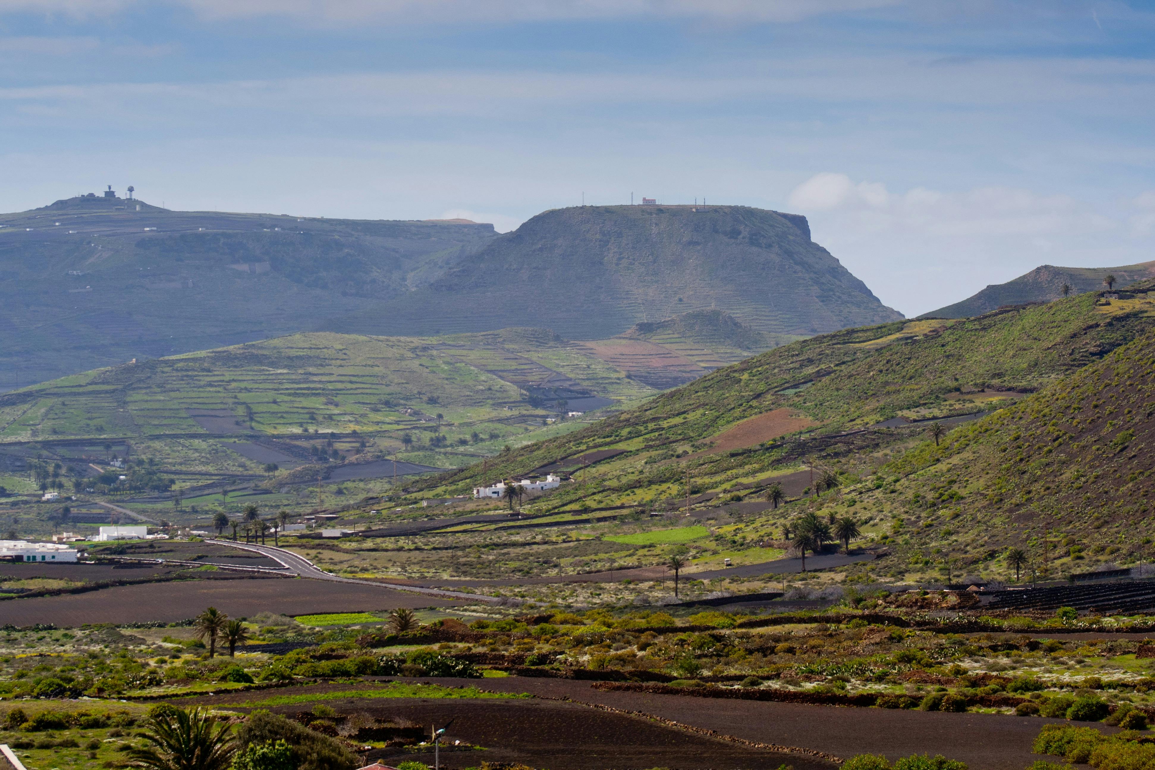 Una valle verde e rigogliosa con campi terrazzati, case sparse e una montagna dalla cima piatta sotto un cielo parzialmente nuvoloso.