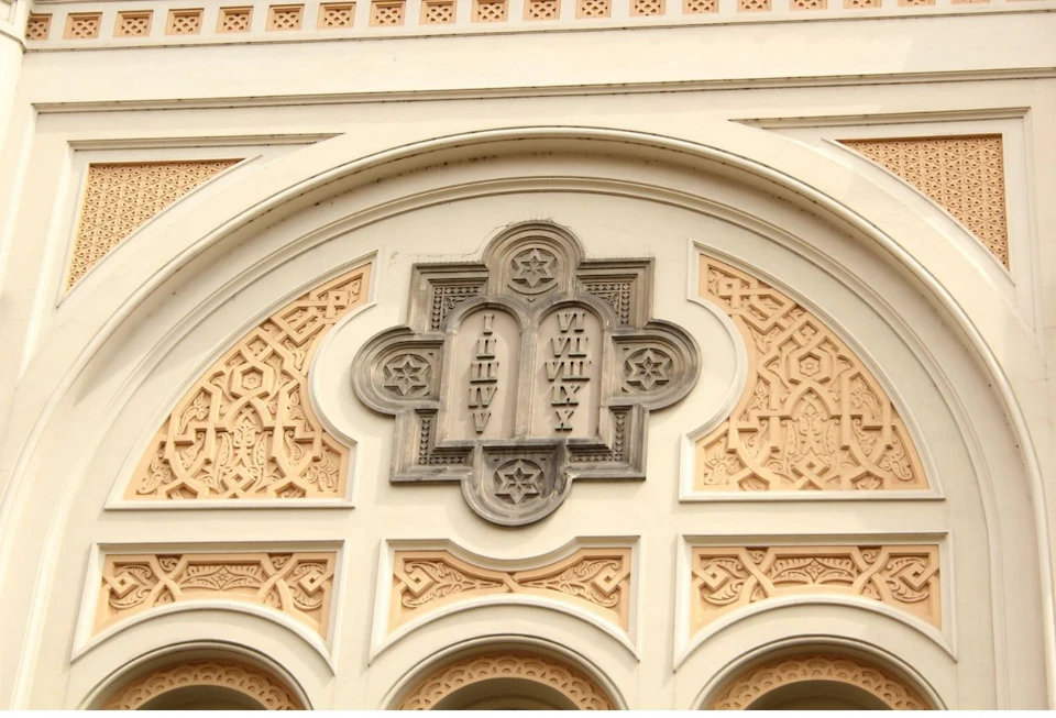 An ornate architectural detail featuring two tablets with Roman numerals and decorative stars set within a beige and white arch.