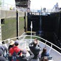 Personas en la proa de un barco Argosy toman fotos de la cámara de cierre, con altos muros de hormigón a ambos lados