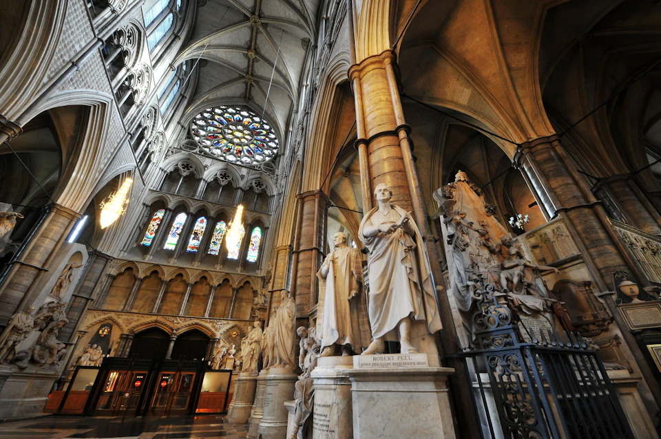 Cathedral interior featuring large stained glass rose window, arched ceiling, and numerous ornate stone statues.