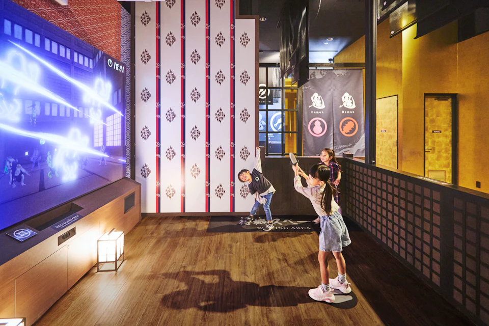 Children playing a game in an indoor setting with interactive walls and wooden flooring.