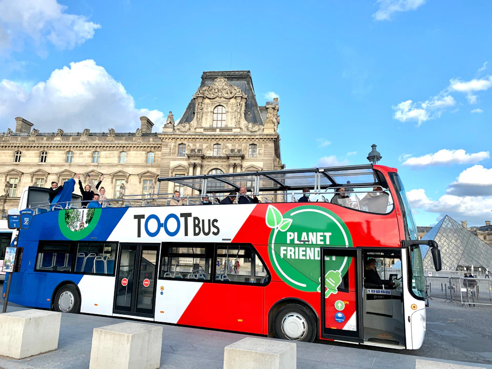 Tootbus Paris double decker bus with French colours passing the Louvre.