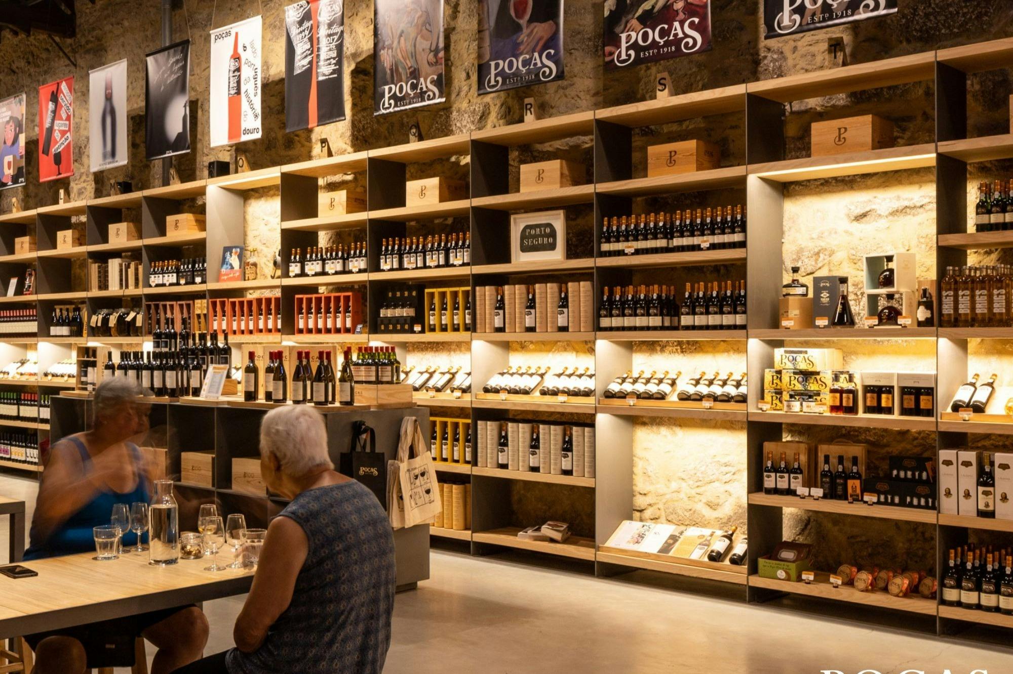 A wine shop interior with shelves of bottles and wooden boxes, a person seated at a table in the foreground.