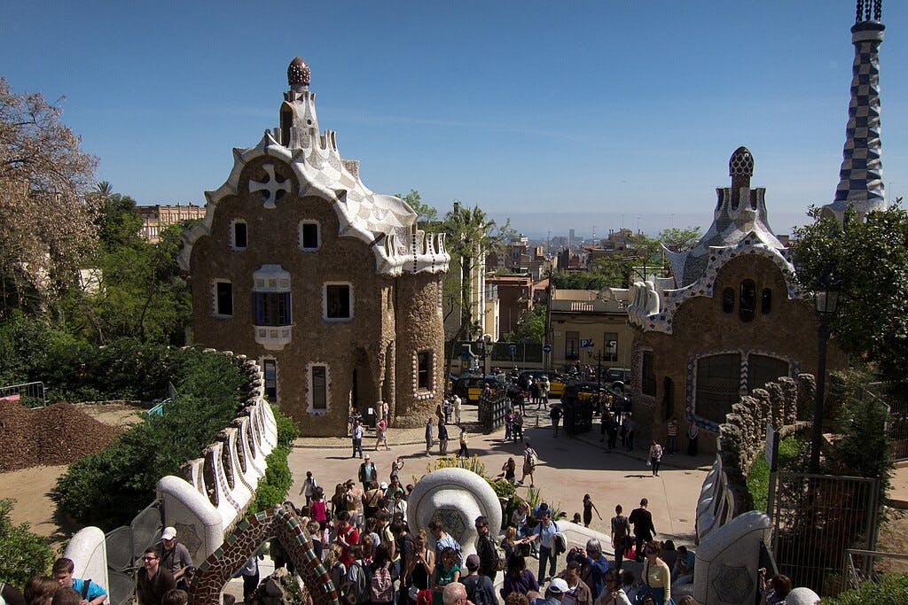 巴塞罗那古埃尔公园（ Park Güell ）的人群，四周环绕着高迪华丽的建筑和雕塑，阳光明媚。