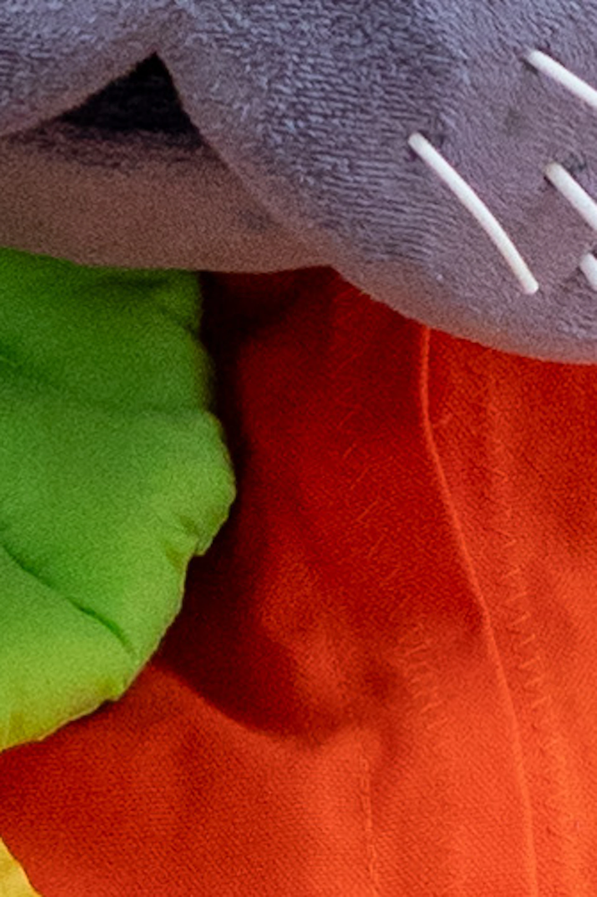 Two children in red and green hats sit beside a person in a manatee costume with a pumpkin-themed shirt.