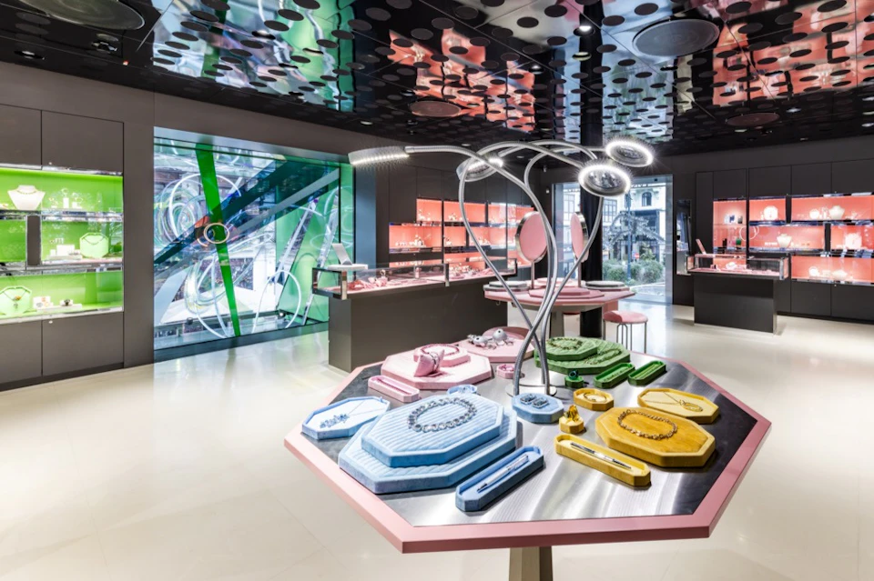 A modern, brightly lit jewelry store with colorful geometric displays and various necklaces showcased under circular lights.