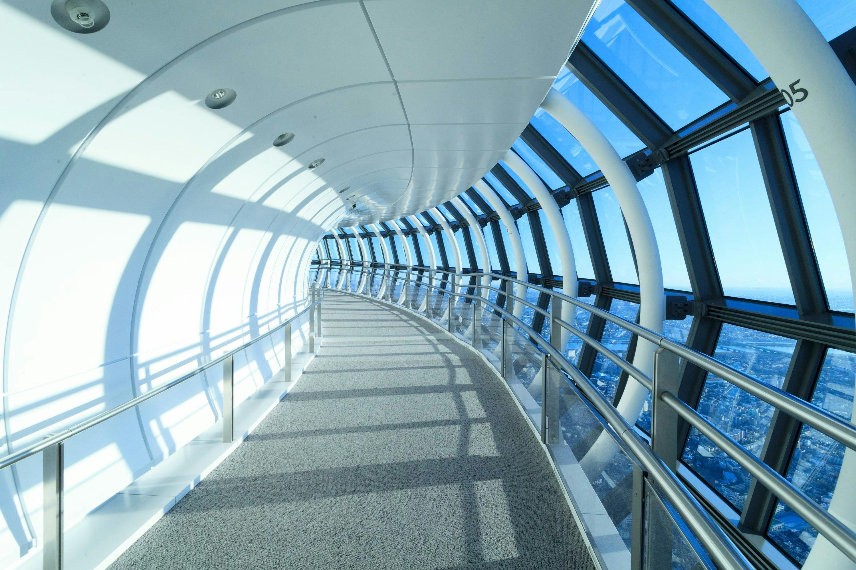 带有金属栏杆的弧形玻璃封闭人行道，一侧可透过大窗户欣赏全景。