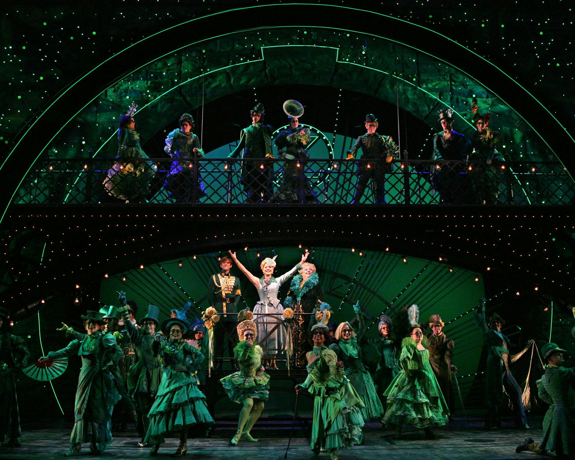 精心设计的绿色服装戏剧演员在绿色照明和星光熠熠的双层舞台上精力充沛地表演。