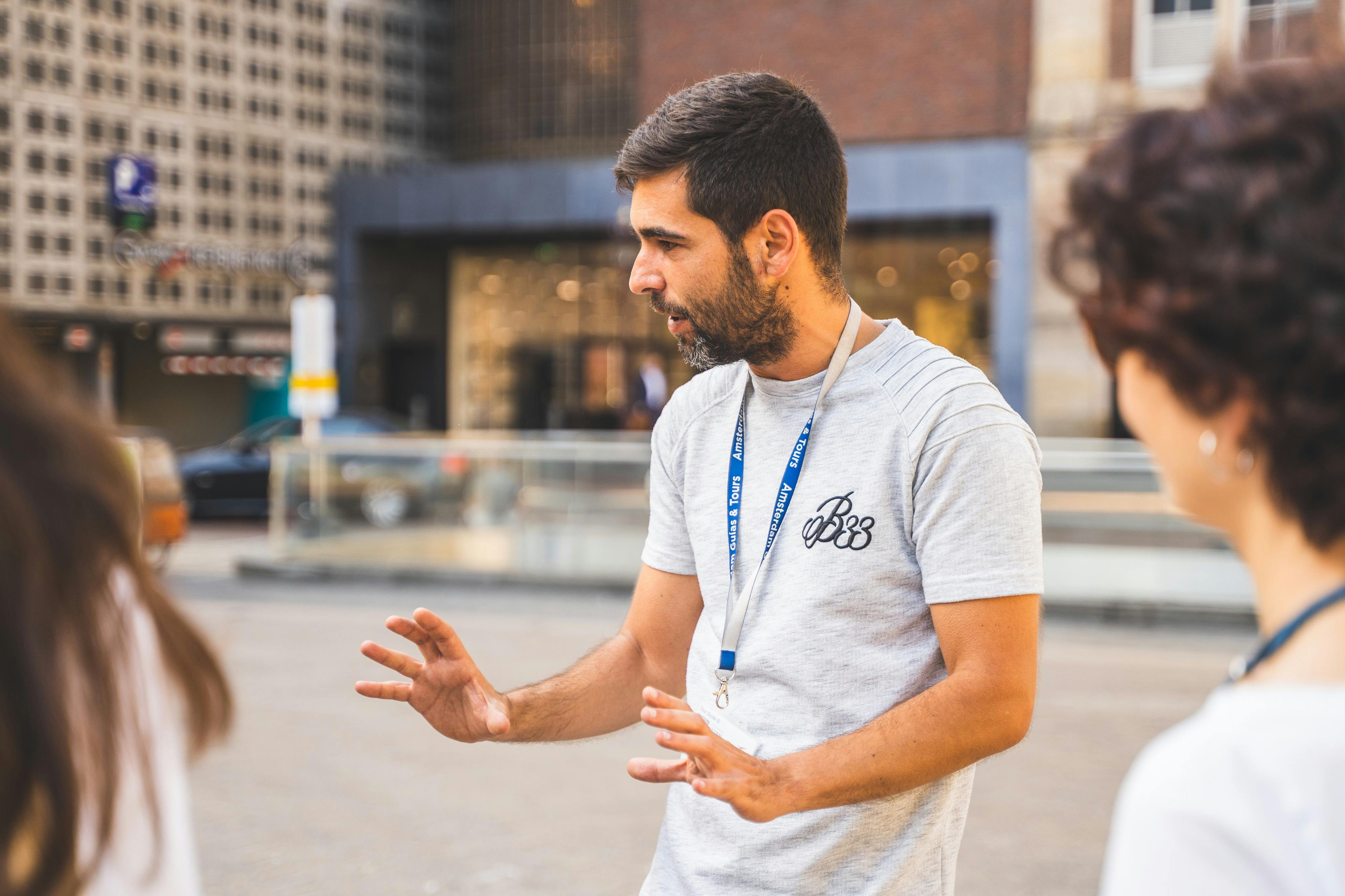 Un home amb barba i camisa grisa i cordó fa un gest amb les mans mentre parla a l'aire lliure.